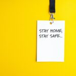 White paper bagde on yellow background lanyard with stay home stay safe sign